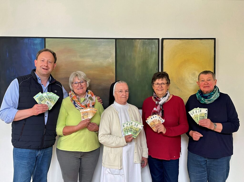 Gruppe lächelnder Menschen übergibt Spende an Hospiz Polling.
