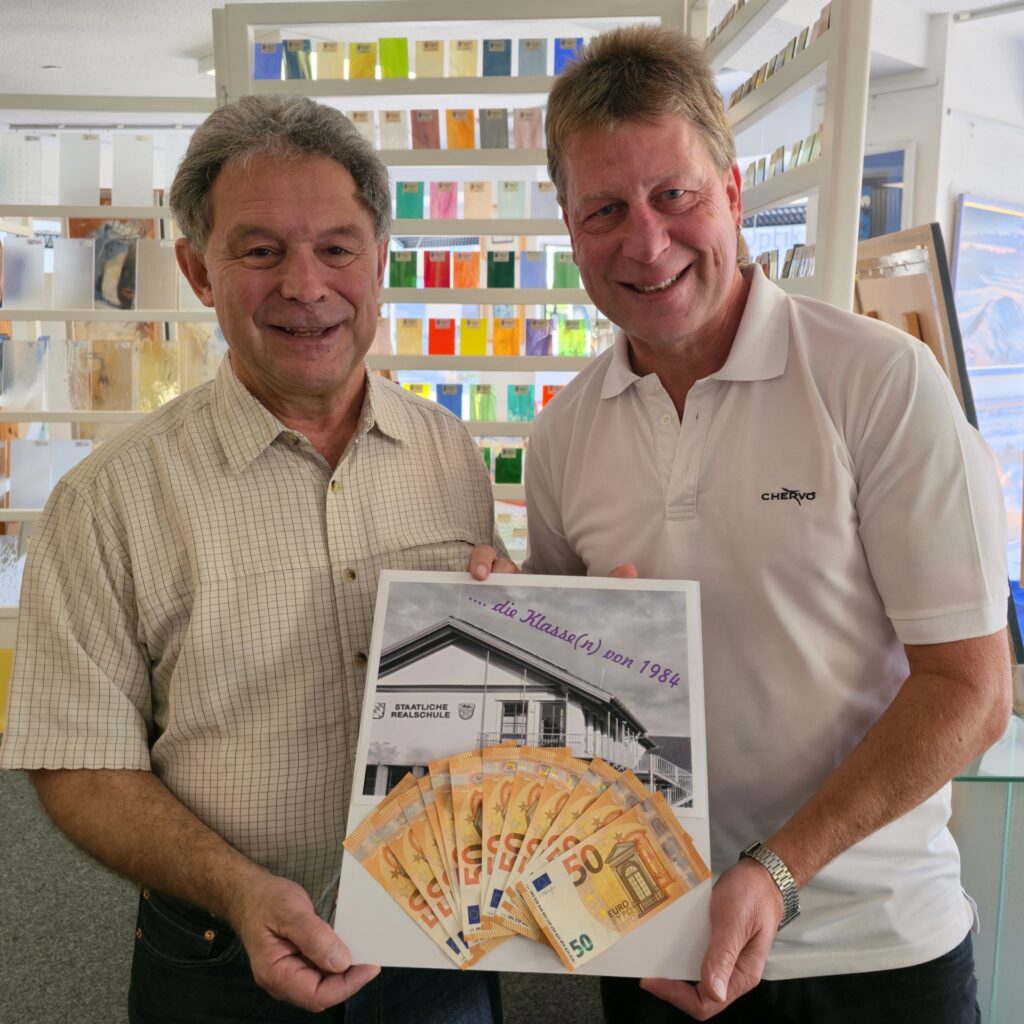 Hospiz Polling - Plakatübergabe, bunte Glasproben im Hintergrund.