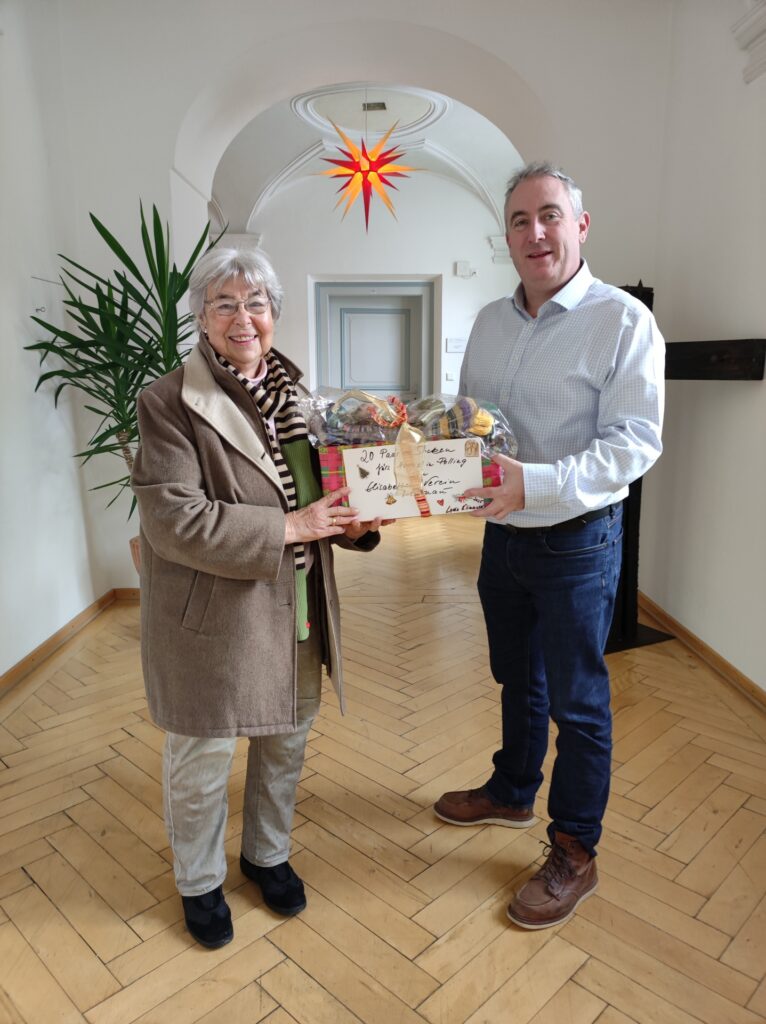 Hospiz Polling - Geschenkübergabe in hellem Raum, festliche Stimmung.