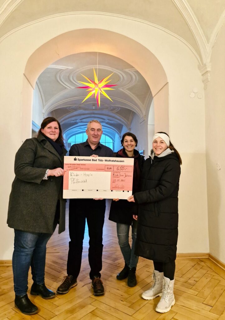 Spendenübergabe Hospiz Polling unter Sternlampe, heller Raum.