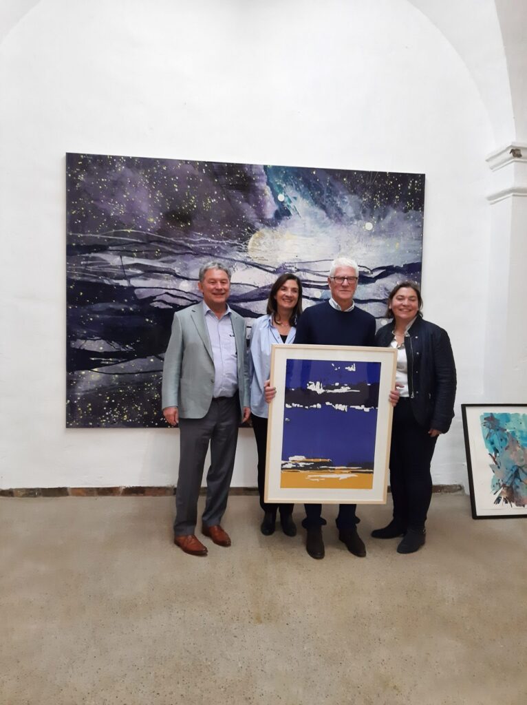 Helle Galerie beim Hospizverein Pfaffenwinkel, Menschen zeigen bunte Kunst.