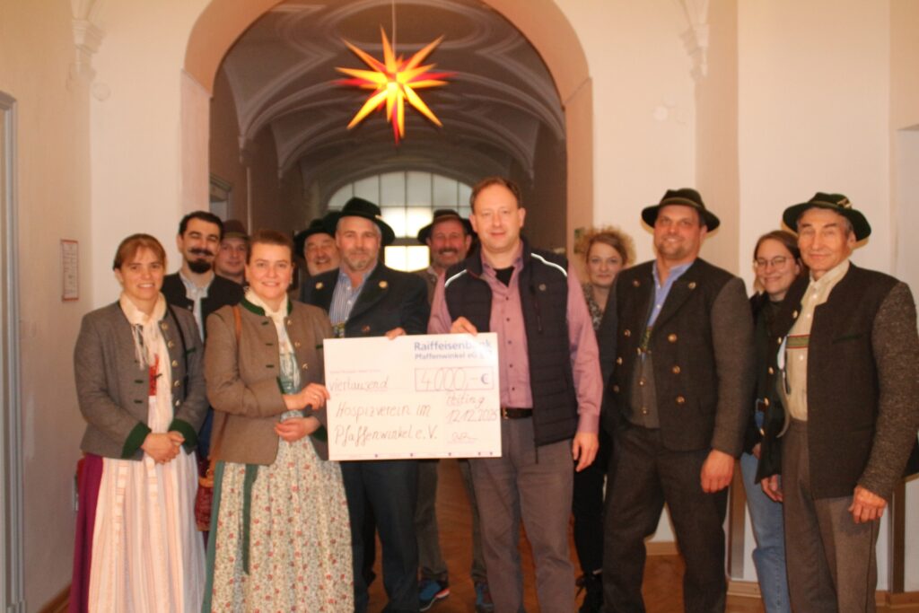 Hospiz Polling: Gruppe in Tracht mit Spendencheck, fröhliche Stimmung.