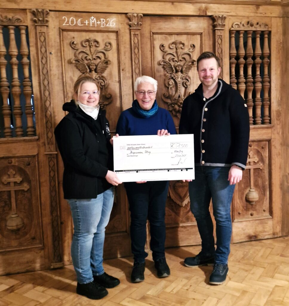 Hospiz Polling - Hospizverein Pfaffenwinkel, Scheckübergabe vor geschnitzter Holztür.