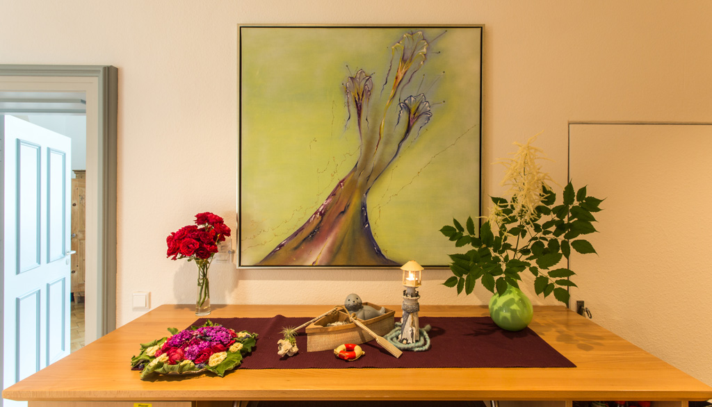 Hospiz Polling - Hospizverein Pfaffenwinkel, bunter Tisch unter abstraktem Baum-Bild.