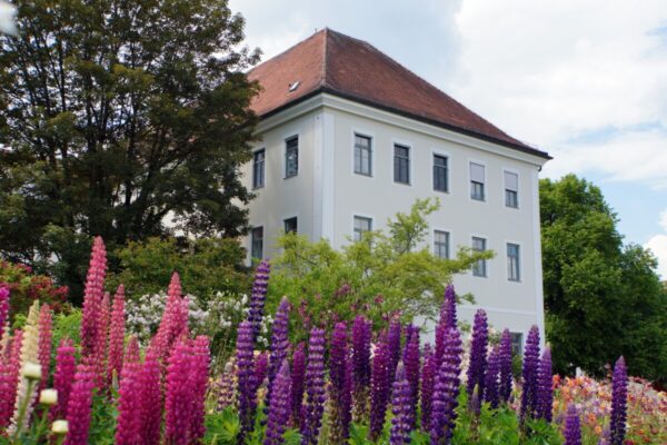 Hospiz Polling - Hospizverein Pfaffenwinkel hinter blühendem Garten.