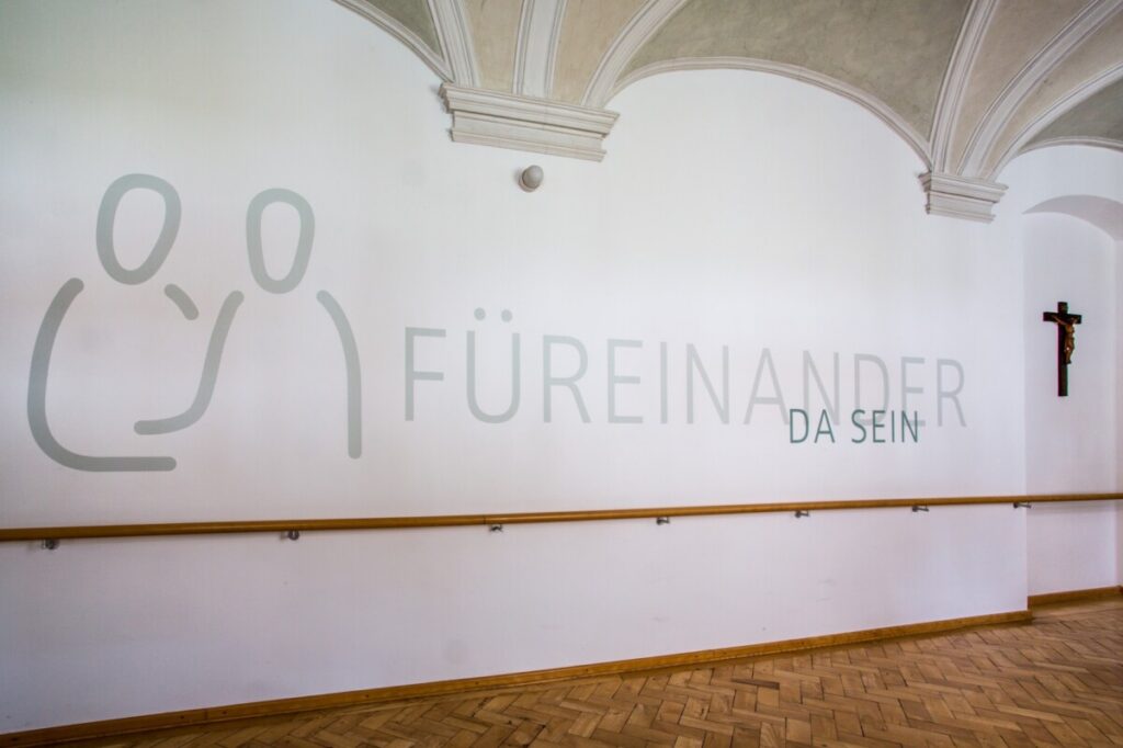 Hospiz Polling - Hospizverein Pfaffenwinkel: Schlichte Kunst, Holzhandlauf, Kreuz.